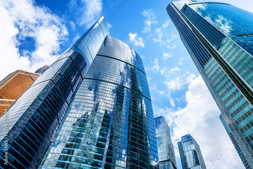 Low angle view of modern glass skyscrapers in financial district. Contemporary corporate architecture symbolizing business, finance and urban development.
