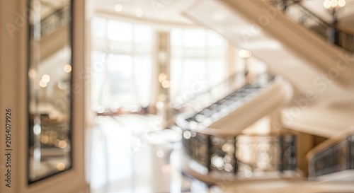 Blurred background of a modern shopping mall interior with escalators and bright natural light.