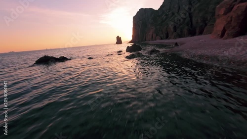 fpv drone flies low over the water of a large sea against the background of the setting sun fast flight over the water waves reflect the sunset evening. High quality 4k footage nobody towards the sun.