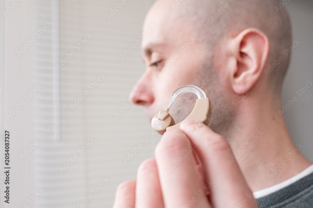 Fototapeta premium close-up hand holding digital BTE hearing aid, solution hearing loss and deafness, medical care, digital audiology, medical solutions hearing loss and deafness in adults, personalized healthcare