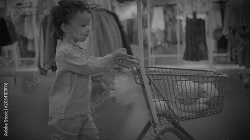 Young child pushing small shopping cart in clothing store aisle