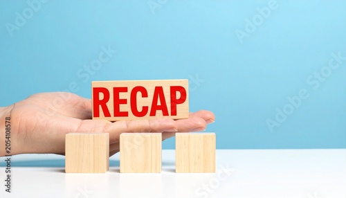 Recap Concept with Wooden Blocks Held by Hand on blue background 