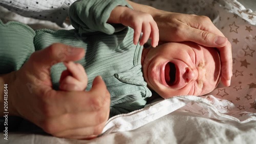 Distressed newborn baby crying loudly while a mother's gentle hands try to soothe and comfort the infant, a poignant close up moment highlighting the challenges and emotions of early parenthood