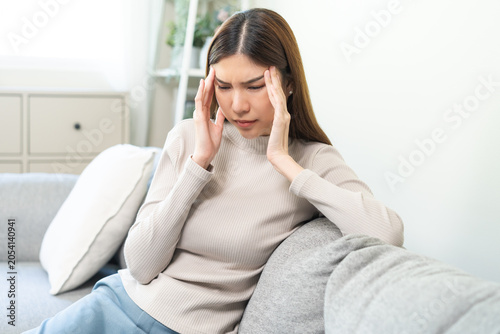Depressed anxiety asian young woman frustrated hand on head, touching her temples, suffering stressed, sick, tired, crisis on sofa from headache, migraine pain tension problem health care concept.