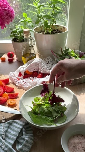 Person preparing fresh summer salad in sunny kitchen