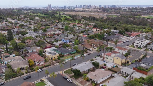 Scenic landscape over a suburban neighborhood of houses and streets with downtown San Diego skyline background, urban sprawl development