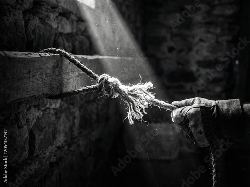 Hand holding frayed rope in a dimly lit stone room, with sunlight streaming through a window, suspense and thriller storytelling, dramatic and moody photography, survival and adventure concepts