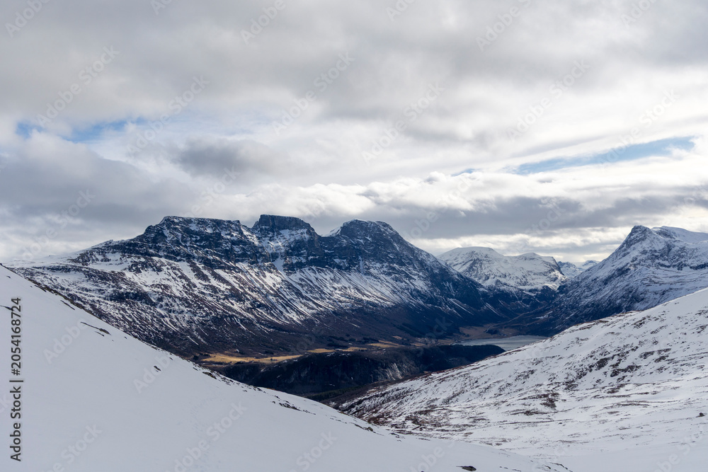 Obraz premium A beautiful winter landscape with snowy mountains in an overcast day. A wintertime scenery near Eidsdal in Geiranger Unesco World Heritage site, More og Romsdale region, Norway.