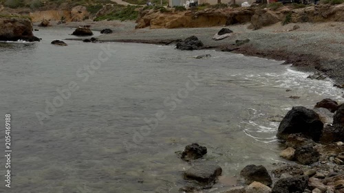 Sea waves lapping against a rocky shore on a cloudy day