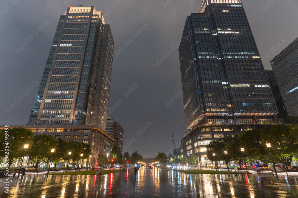 Obraz premium 雨の東京駅前にそびえる丸ビルの夜景 Rainy Night View of Marunouchi Building Near Tokyo Station, Japan