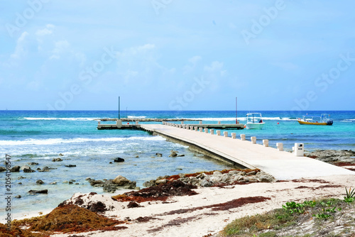 Pier extending into the ocean with boats nearby.