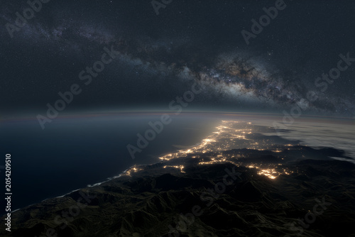 Littoral d'une ville balnéaire vu de nuit depuis l'espace sous la Voie Lactée.
