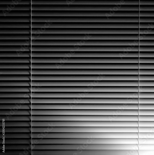 Venetian window blinds at night with glow from lamp light in black and white monochrome