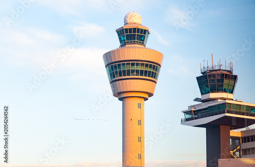 Modern airport air traffic control towers under a bright blue sky at sunset
