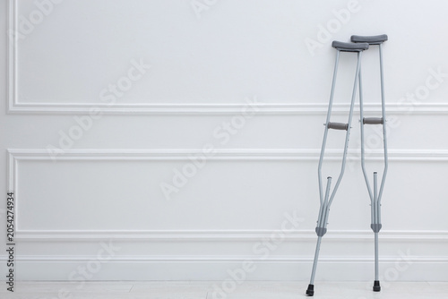 Φωτογραφία Metal axillary crutches near white wall, space for text