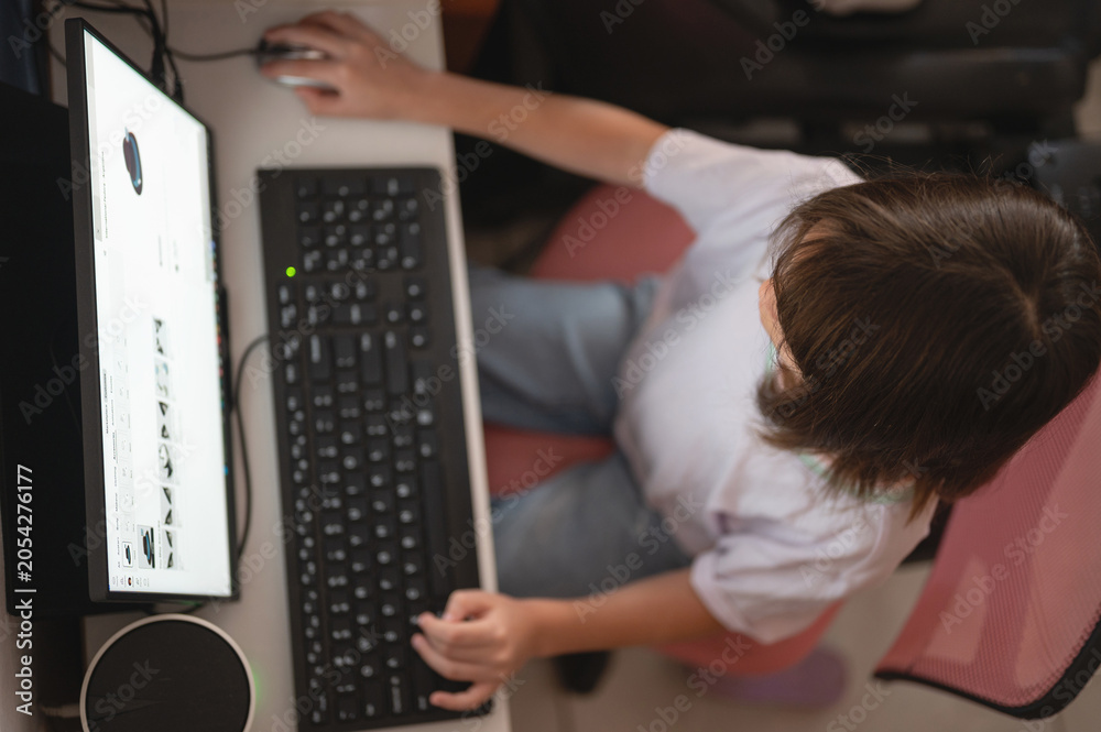 Fototapeta premium Child uses computer at home for study or play