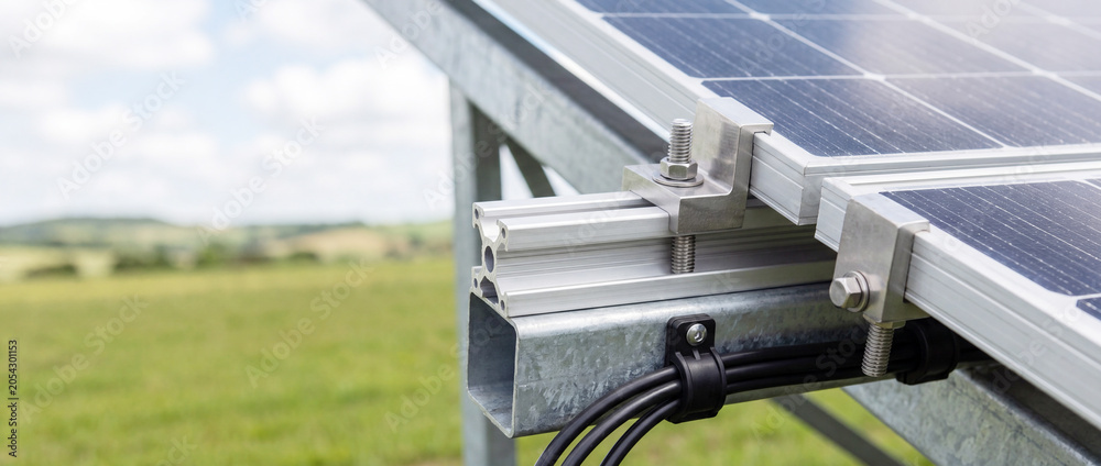 Naklejka premium Close-up of solar panel mounting and cables on ground-mounted solar array in countryside