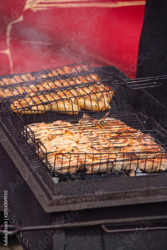 Grilled chicken and fish on barbecue grill with smoke rising
