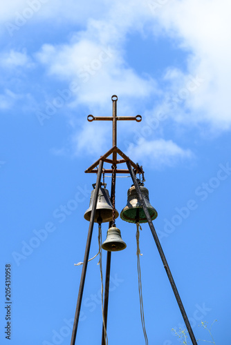 Old church bells and cross against blue sky