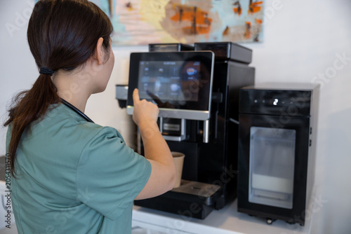 Foto Tired female doctor making herself coffee in a hospital kitchen