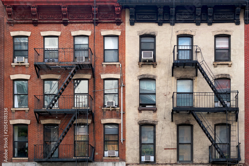 Fotografie Exterior view of a classic apartment building facade in midtown New York with symmetrical rows of windows, brick masonry, and traditional exterior emergency stairs