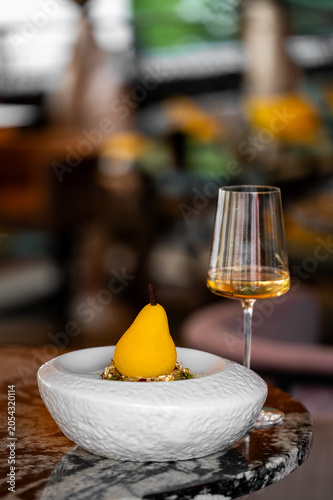 Εκτύπωση καμβά A pear-shaped dessert served in a white ceramic bowl next to a glass of white wine on a marble table
