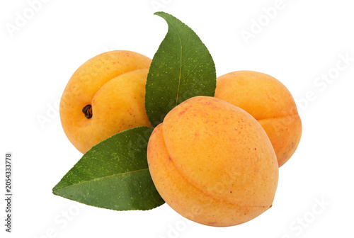 Foto Group of ripe apricots and green leaves isolated on a dark setting