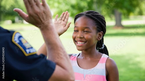 Police officer giving high five to smiling child during community outreach event, positive neighborhood engagement, youth trust building and local law enforcement connection, open house day