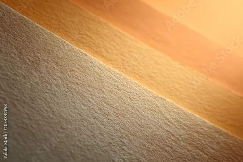 Abstract textured paper background in warm beige and orange tones, featuring diagonal layers and soft lighting. Minimalist design perfect for creative projects and modern branding