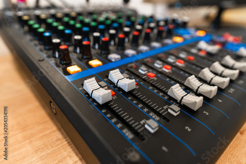 Close up of professional audio mixing console with colorful knobs and faders in a recording studio, selective focus.