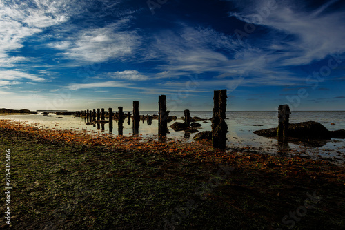 Φωτογραφία Helgoland coastal posts recede across quiet tidal shore beneath sweeping blue sk