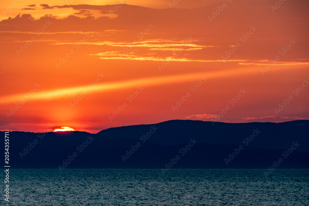 Fototapeta premium Bunter Wolkenhimmel nach Sonnenuntergang am Meer