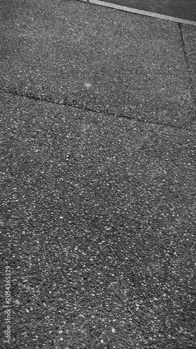 Vertical format of plain asphalt pavement or sidewalk, in black and white.