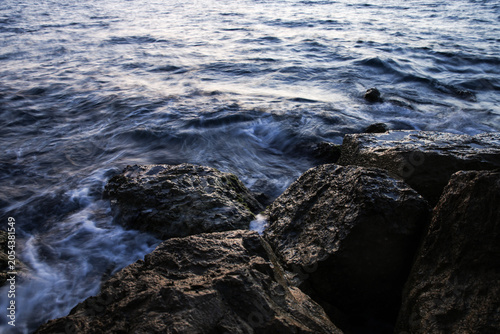 Artistic Long Exposure Photography of Rushing Ocean Waves Crashing Over Rugged Dark Coastal Rocks at Twilight