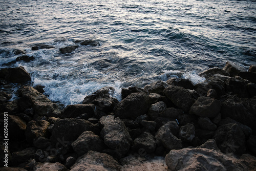 Artistic Long Exposure Photography of Rushing Ocean Waves Crashing Over Rugged Dark Coastal Rocks at Twilight