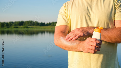 Фотография Sunscreen cream applied to arm in outdoor lakeside setting