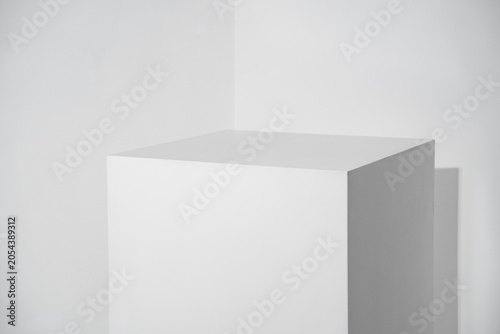 White wooden cube on the background of a light wall in a room, geometric shape