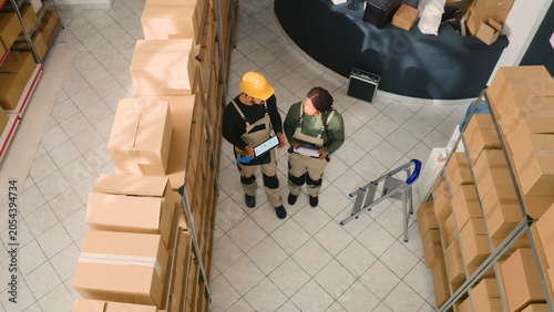 Φωτογραφία Jib up shot of warehouse sorters comparing findings after finishing inspecting cardboard box parcels
