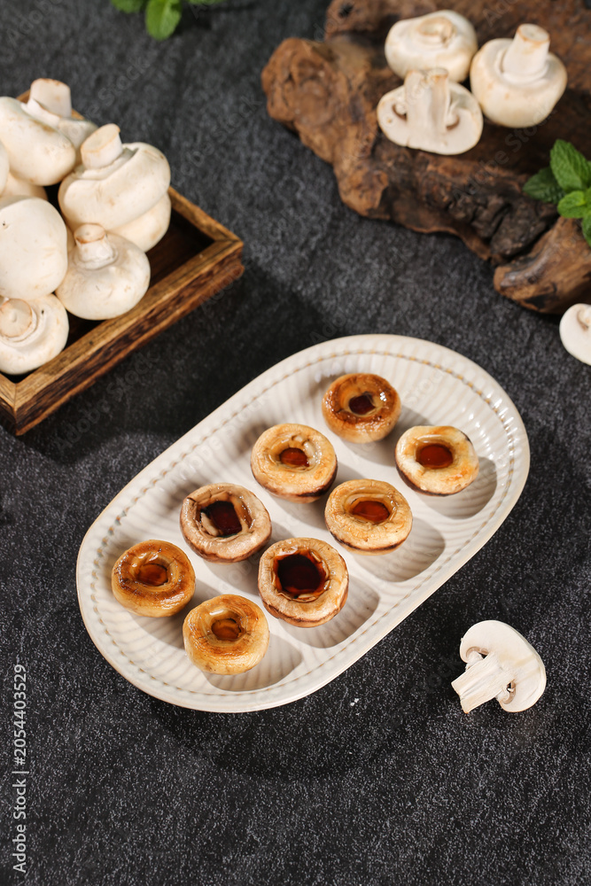 Fototapeta premium Sautéed White Mushrooms with Fresh Wild Mushroom Produce on Dark Slate Kitchen Background