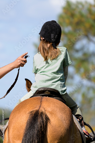 Tableau sur toile Child rides horse under bright sky