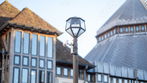 Street lamp post with security camera in front of historic building exterior
