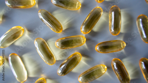 Golden transparent gel capsule scattered on light surface in macro close view