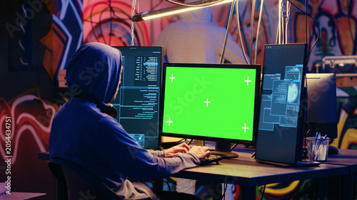 Foto Hackers using green screen PC to code malware designed to exploit network backdoors, Cybercriminals use mockup monitor while bypassing security measures in graffiti painted bunker