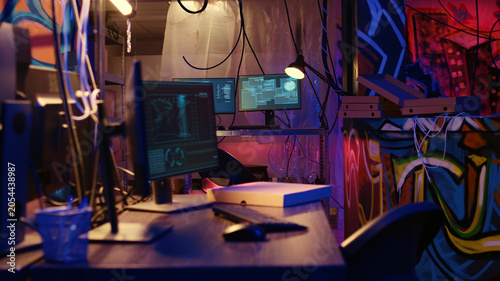 Obraz na plátne Dolly out shot of empty messy hackers base of operations with neon lights and graffiti drawings sprayed on walls, Ghetto hideout used by criminals to commit illegal activities using computers