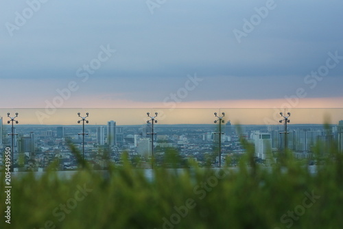Photography Rooftop view of a sprawling city skyline at dusk with a glass railing and greene