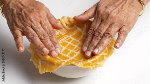 A person skillfully shaping a vibrant yellow pastry dough into a delicate crust in a video.