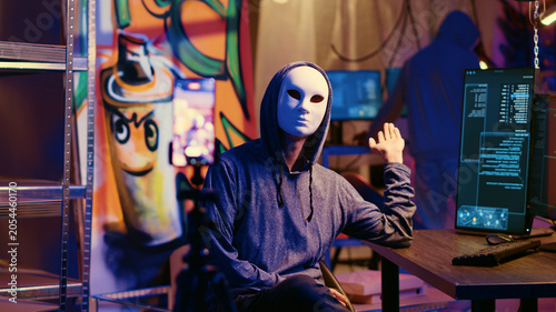 Tableau sur toile Masked hackers filming ransom video in hidden underground base, threatening to release stolen data publicly if payout demands are not met, Rogue programmers using phone to record blackmail footage