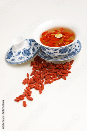 Foto Goji Berry Tea in Blue and White Porcelain Bowl with Dried Berries