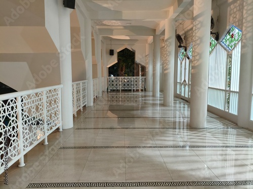 Interior view of a modern mosque with white pillars and patterned railings