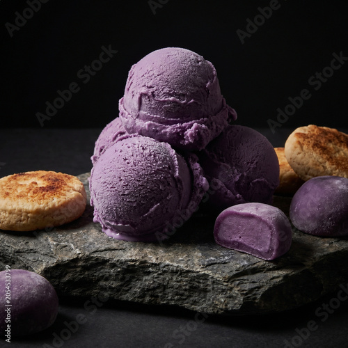 Ube ice cream scoops and cookies displayed on a stone
